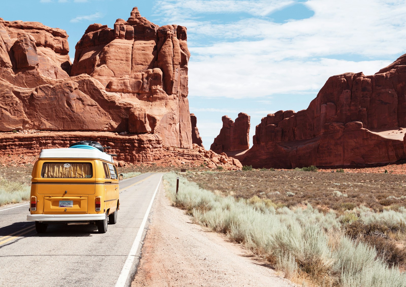 Tour van driving through a desert highway at golden hour